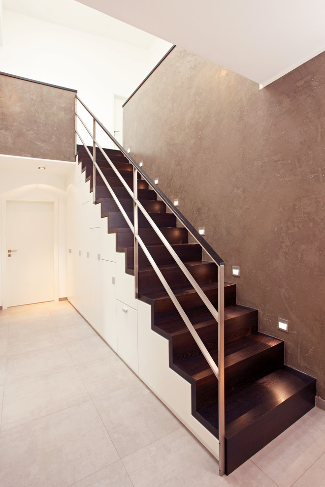 Imagen de escalera recta actual grande con barandilla de metal, escalones de madera y contrahuellas de madera