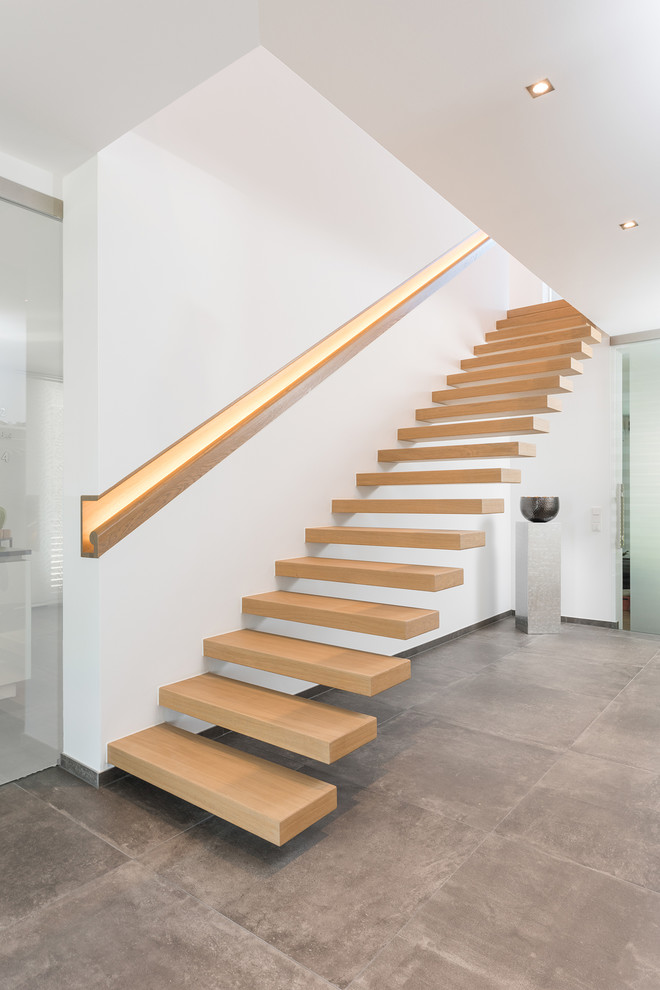 Imagen de escalera suspendida minimalista de tamaño medio con escalones de madera y barandilla de madera