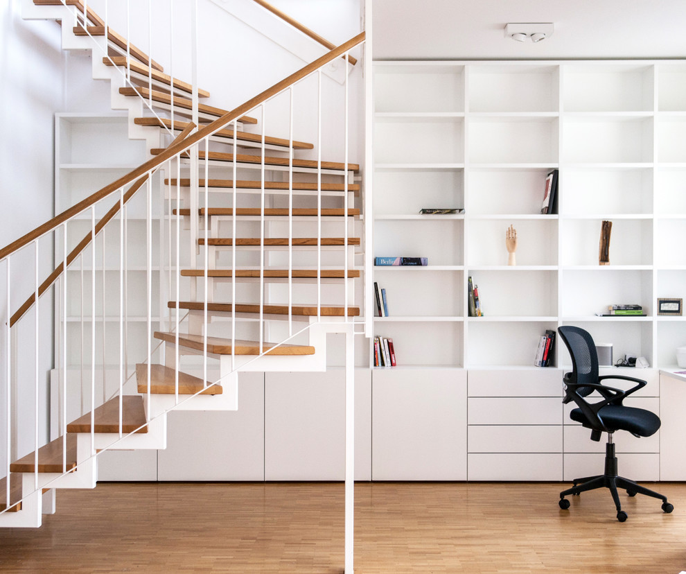 Imagen de escalera curva minimalista grande sin contrahuella con escalones de madera pintada y barandilla de varios materiales