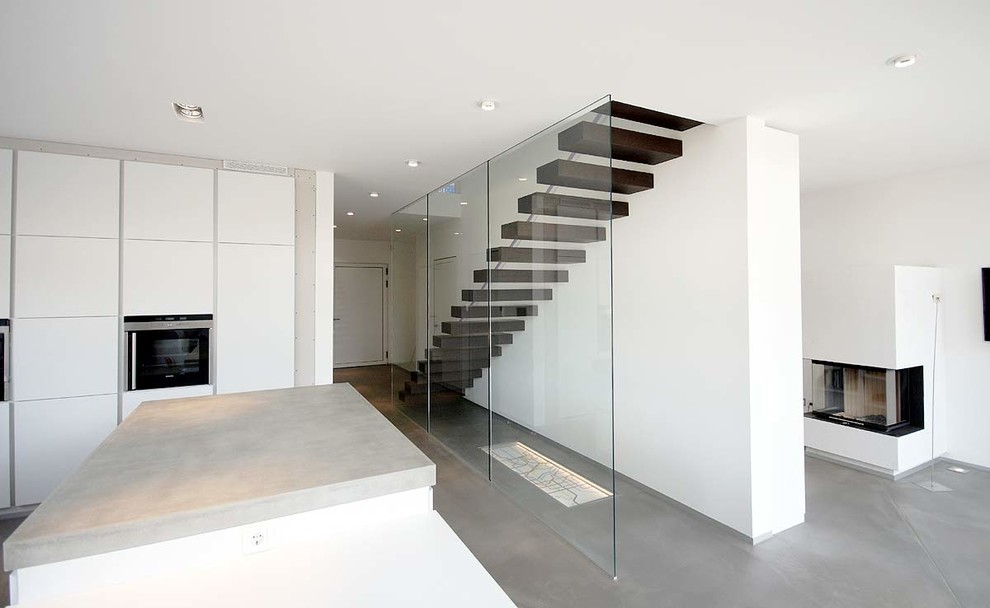 Ejemplo de escalera recta contemporánea grande sin contrahuella con escalones de madera y barandilla de vidrio