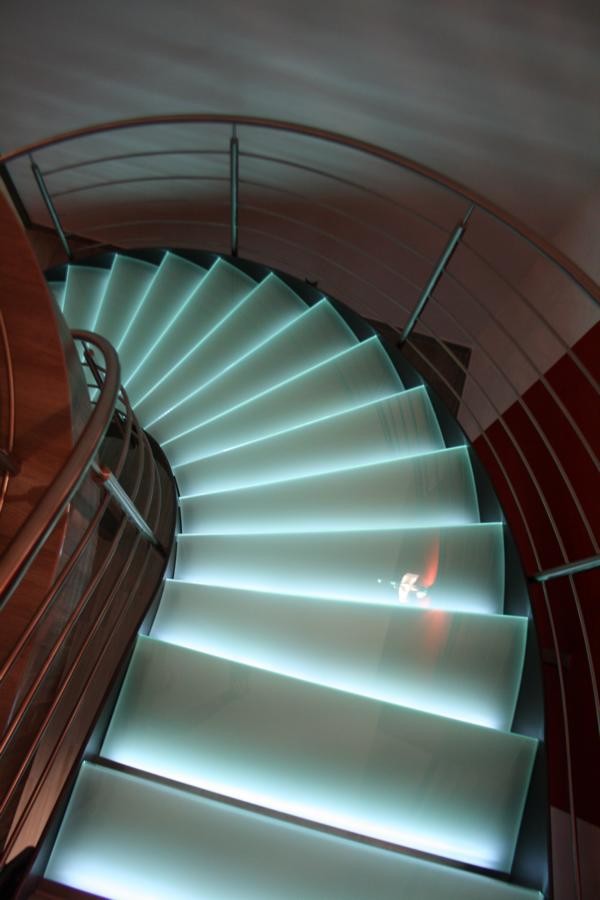 Modern inredning av en stor svängd trappa i glas, med öppna sättsteg