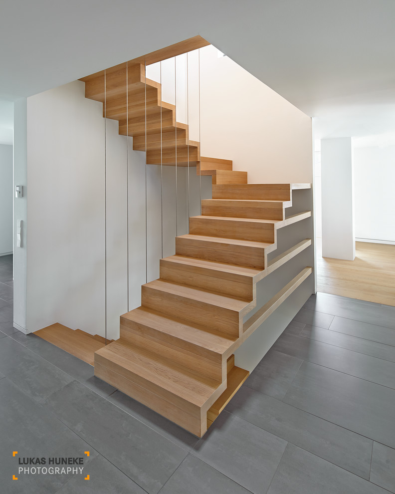 Aménagement d'un très grand escalier flottant contemporain avec des marches en bois et des contremarches carrelées.