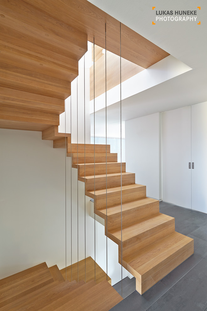 Idée de décoration pour un très grand escalier flottant design avec des marches en bois et des contremarches carrelées.