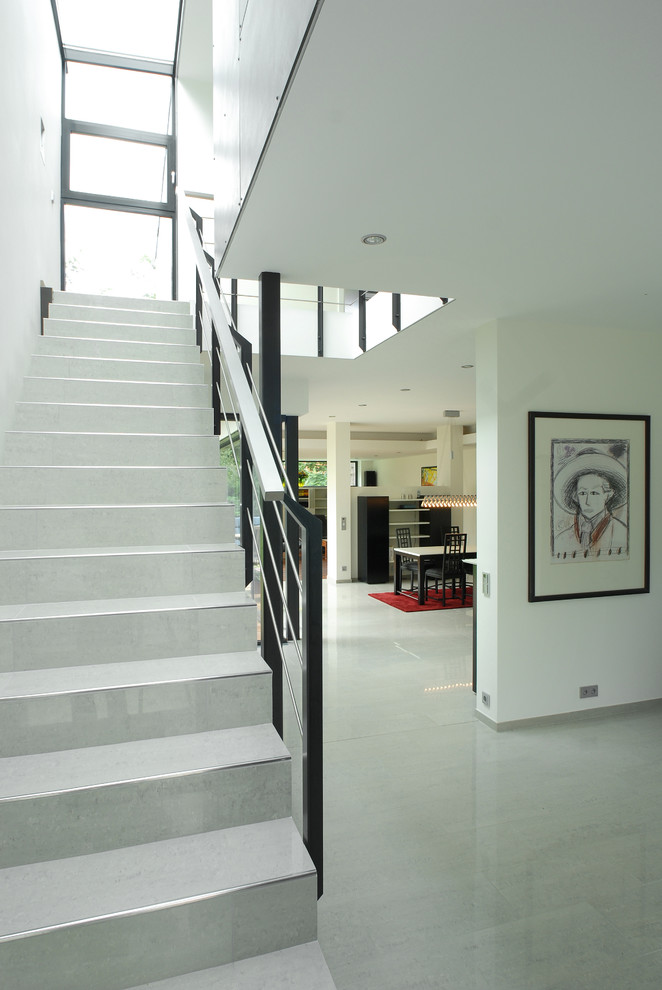 Foto de escalera suspendida minimalista de tamaño medio con escalones con baldosas, contrahuellas con baldosas y/o azulejos y barandilla de metal