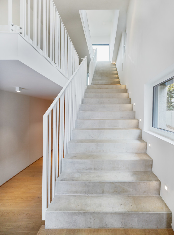 Diseño de escalera recta minimalista extra grande con escalones de hormigón, contrahuellas de hormigón y barandilla de metal