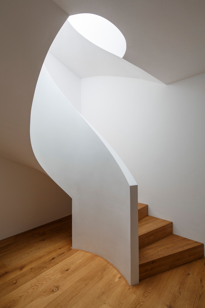 Inspiration for a contemporary wooden spiral staircase remodel in Cologne with carpeted risers