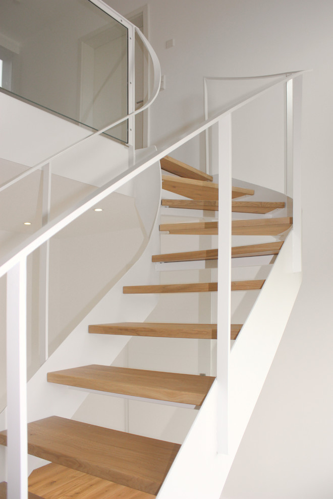 Imagen de escalera curva moderna con escalones de madera y barandilla de metal
