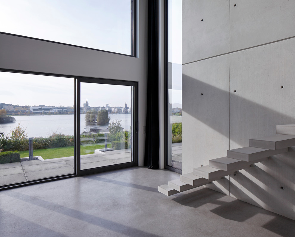 На фото: огромная прямая лестница в стиле модернизм с бетонными ступенями без подступенок с