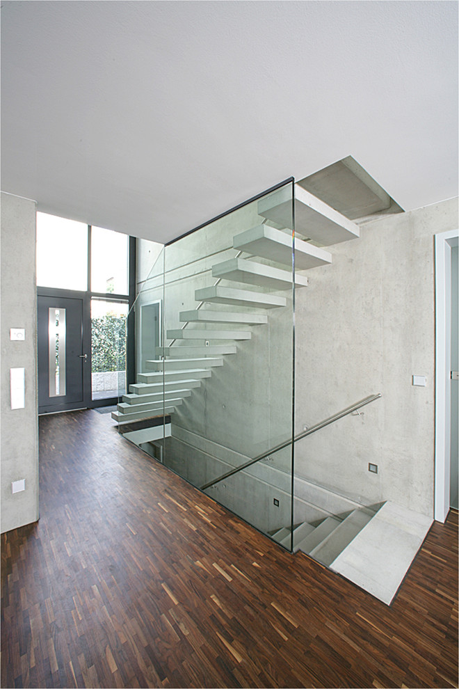 Idée de décoration pour un escalier sans contremarche flottant minimaliste en béton de taille moyenne avec un garde-corps en verre.