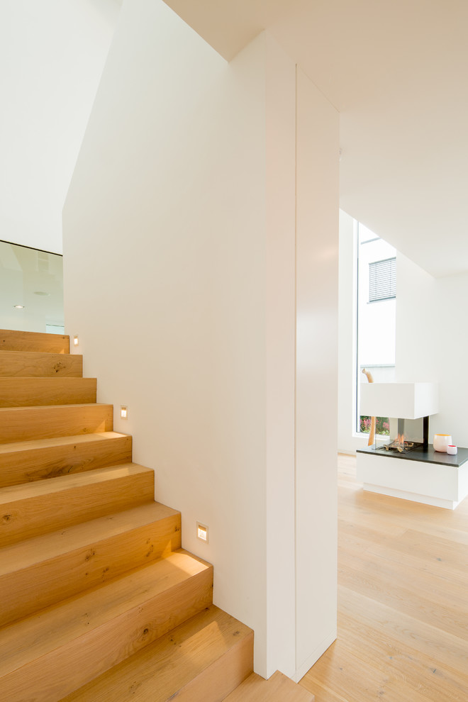 Idées déco pour un escalier droit contemporain de taille moyenne avec des marches en bois, des contremarches en bois et éclairage.