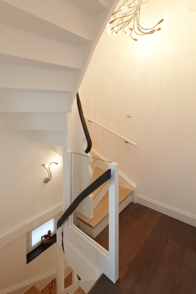 Imagen de escalera curva clásica pequeña con escalones de madera y contrahuellas de madera