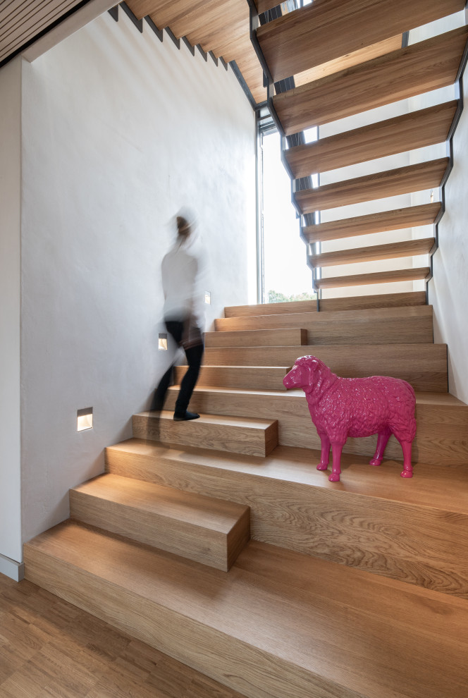 Ejemplo de escalera en U escandinava grande con escalones de madera, contrahuellas de madera y barandilla de metal