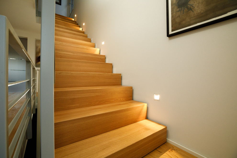 Exemple d'un escalier moderne avec des marches en bois, des contremarches en bois et un garde-corps en métal.