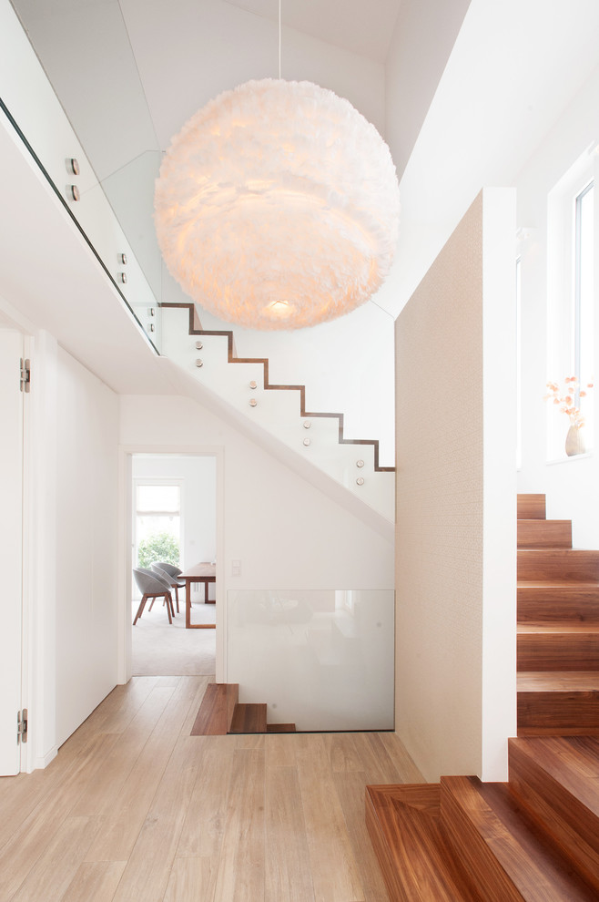 Cette photo montre un escalier tendance en U avec des marches en bois, des contremarches en bois et un garde-corps en verre.