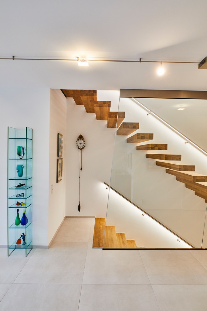 На фото: лестница среднего размера, на больцах в современном стиле с крашенными деревянными ступенями и металлическими перилами с