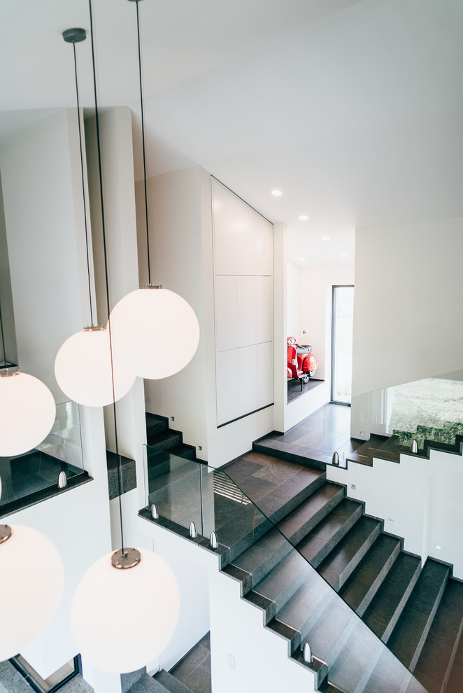 Inspiration pour un grand escalier carrelé droit minimaliste avec des contremarches carrelées, un garde-corps en verre et éclairage.