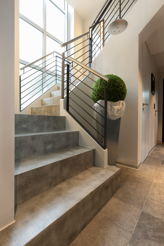 Inspiration for an expansive contemporary concrete u-shaped metal railing staircase in Other with concrete risers.