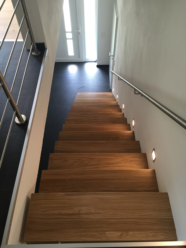 Diseño de escalera suspendida minimalista grande sin contrahuella con escalones de madera y barandilla de metal