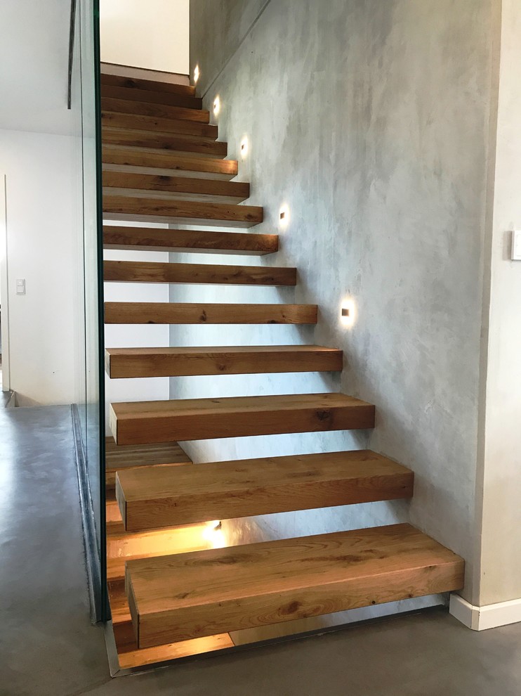 Modelo de escalera suspendida minimalista grande con escalones de madera, barandilla de vidrio y contrahuellas de madera