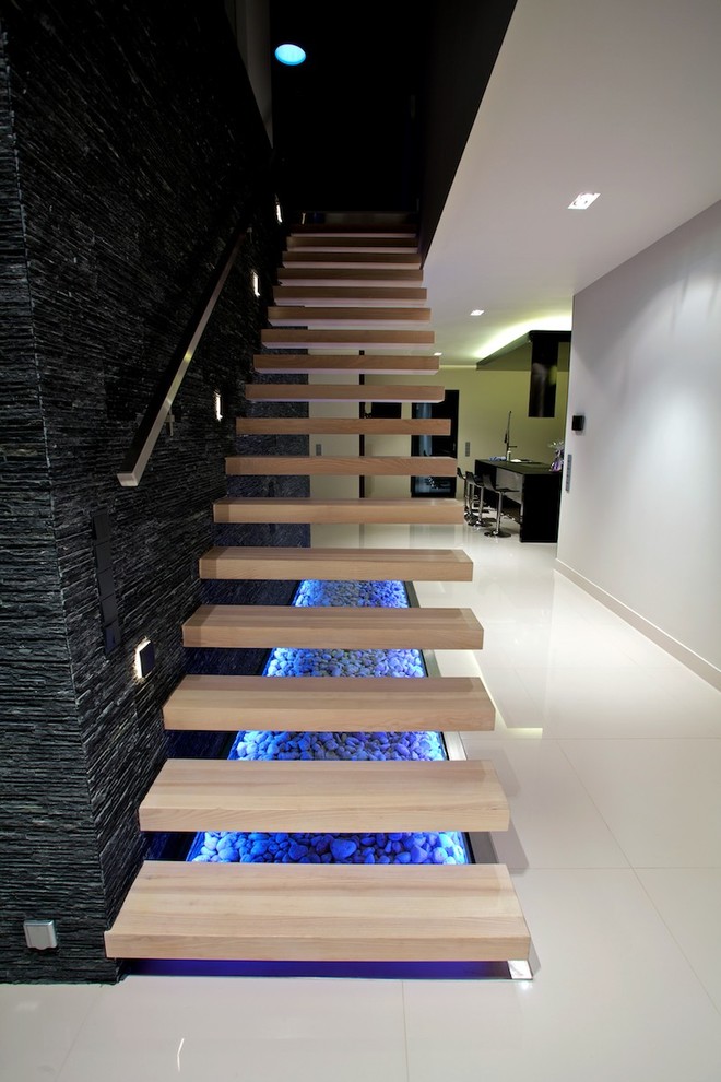 На фото: лестница на больцах в стиле модернизм с деревянными ступенями, металлическими перилами и панелями на стенах без подступенок с