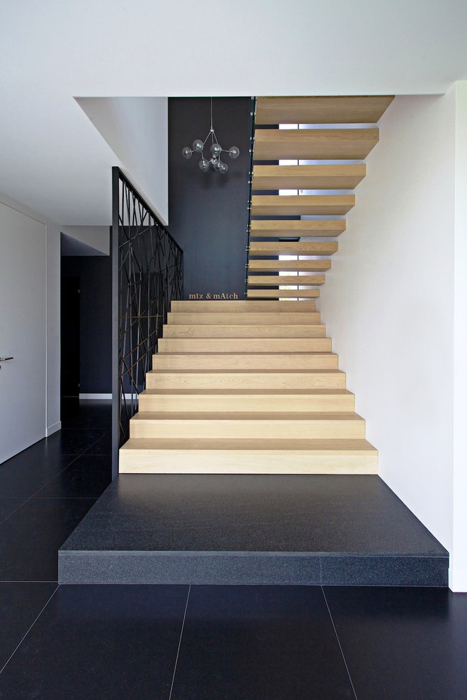 Bild på en stor funkis flytande trappa i trä, med öppna sättsteg