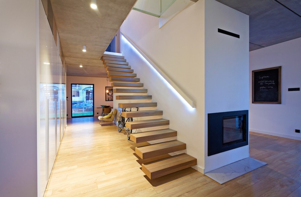 Стильный дизайн: большая лестница на больцах в стиле модернизм с деревянными ступенями без подступенок - последний тренд