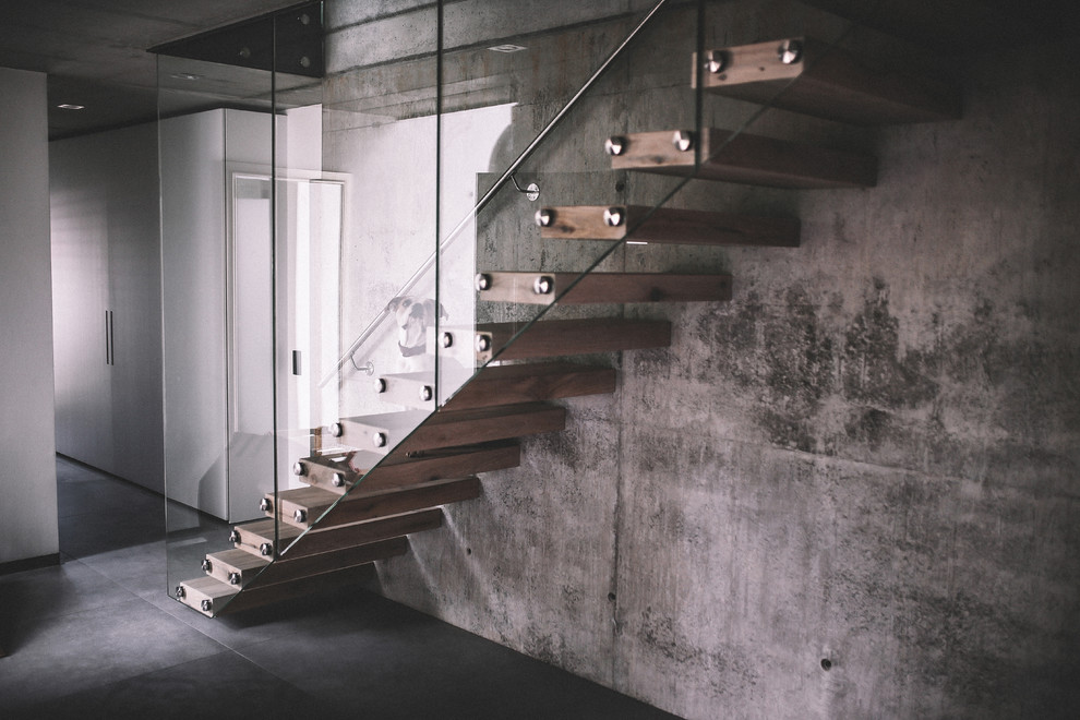 Aménagement d'un grand escalier sans contremarche flottant moderne avec des marches en bois et un garde-corps en verre.