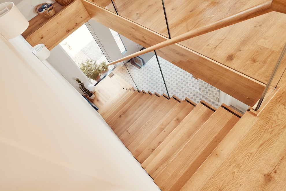 Стильный дизайн: угловая лестница среднего размера в стиле модернизм с деревянными ступенями и стеклянными перилами - последний тренд