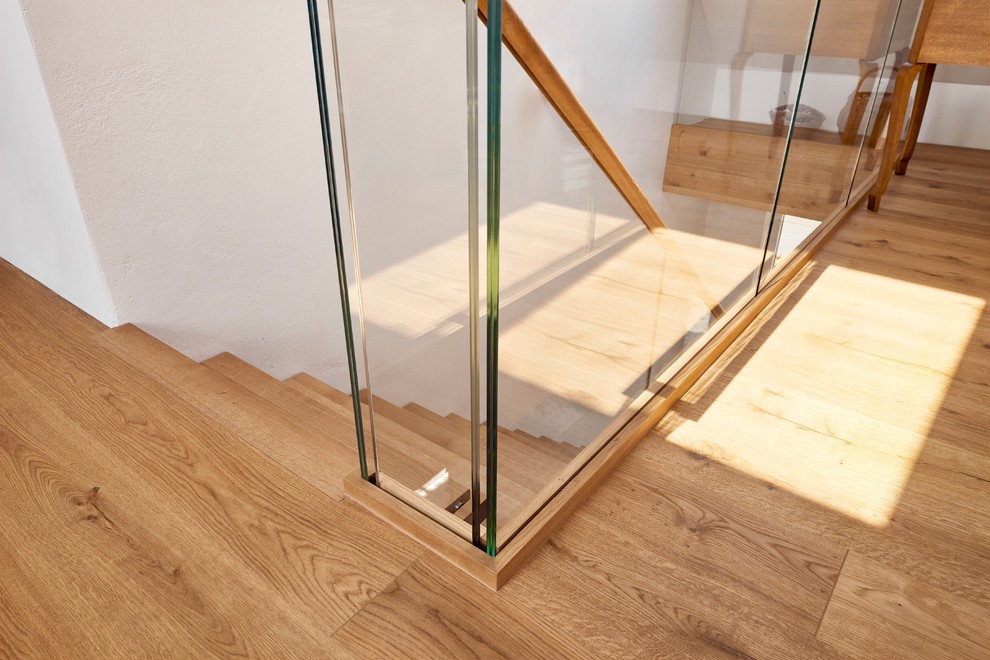 Photo of a medium sized modern wood l-shaped glass railing staircase in Dortmund.