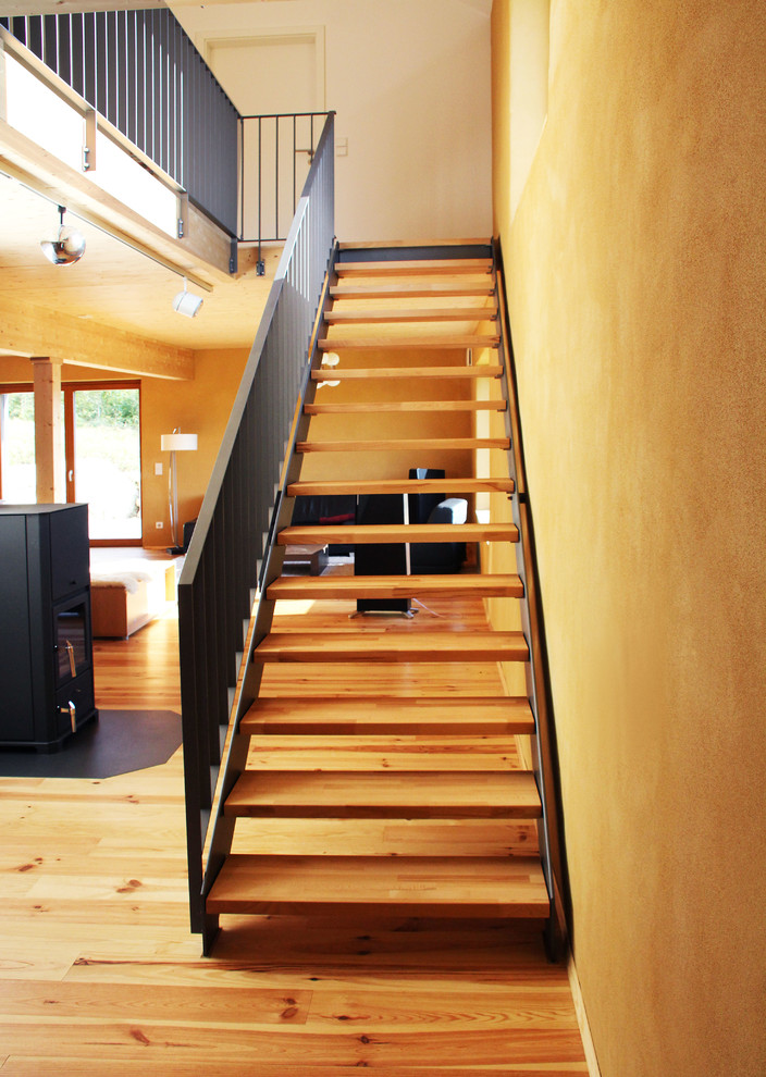 Ejemplo de escalera recta contemporánea de tamaño medio con escalones de madera y barandilla de metal