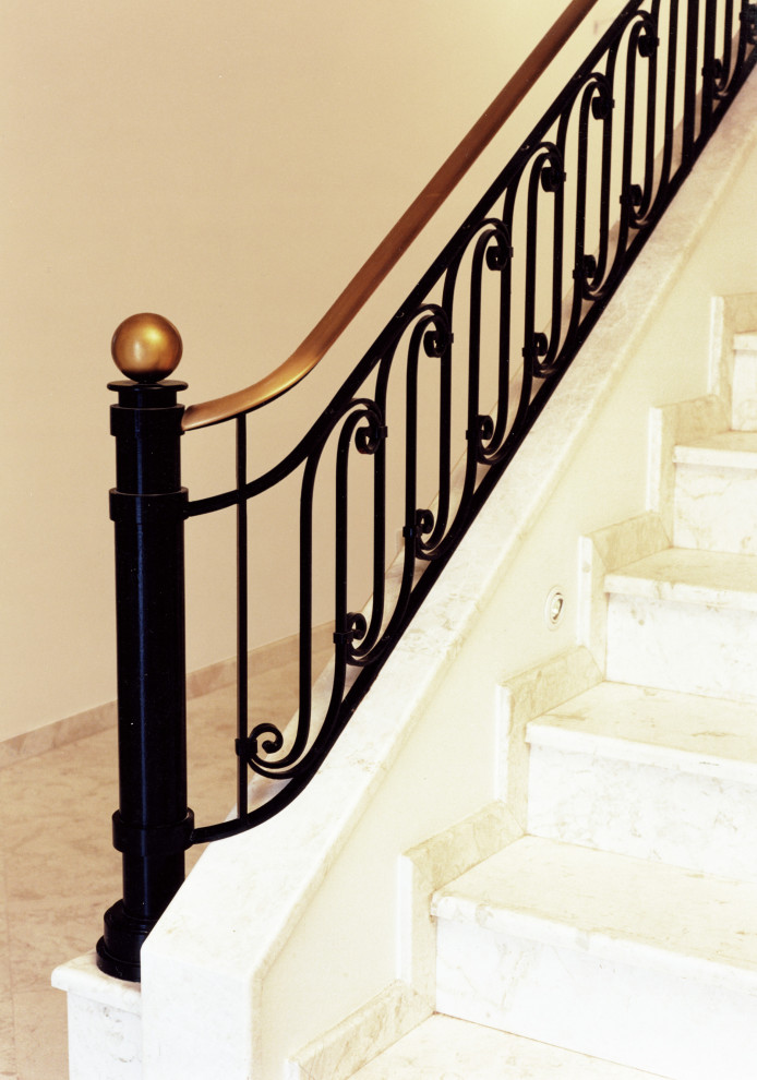 Photo of a large classic straight metal railing staircase in Dusseldorf with marble treads and marble risers.
