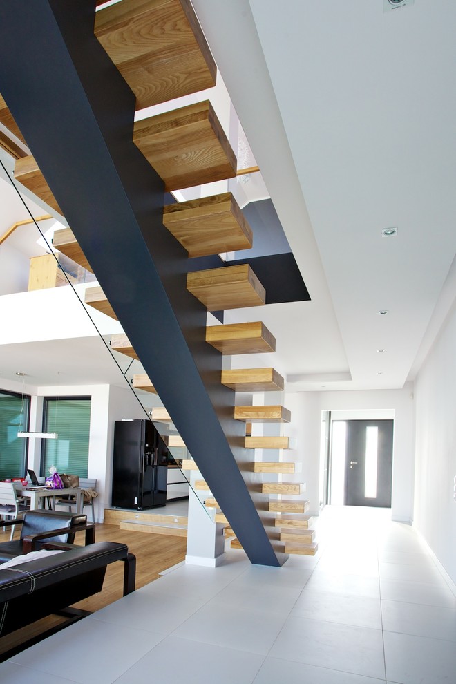 Foto di una grande scala a rampa dritta design con pedata in legno e nessuna alzata