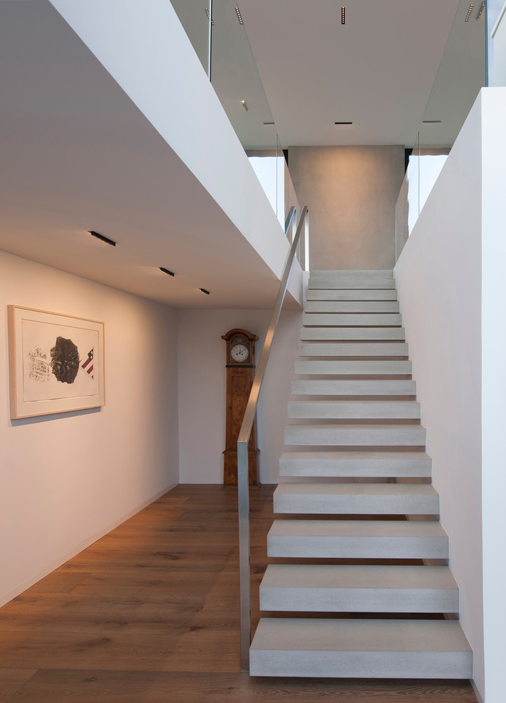 Imagen de escalera recta minimalista de tamaño medio con escalones de hormigón y barandilla de metal