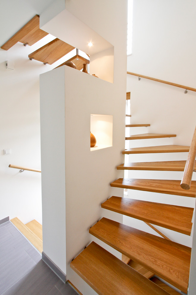 Medium sized contemporary wood curved staircase in Hamburg with open risers.