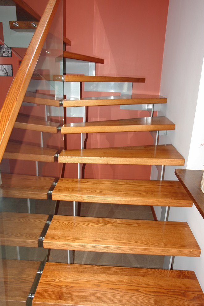 Mittelgroße, Gewendelte Moderne Treppe mit gebeizten Holz-Treppenstufen und offenen Setzstufen in München