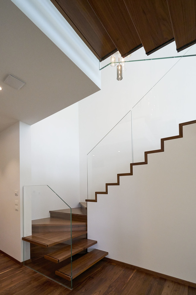 Photo of a medium sized modern painted wood curved glass railing staircase in Munich with open risers.
