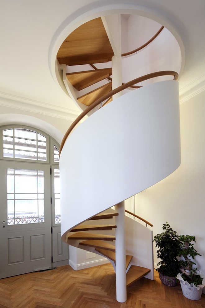 Foto di una grande scala a chiocciola design con pedata in legno, parapetto in legno e nessuna alzata