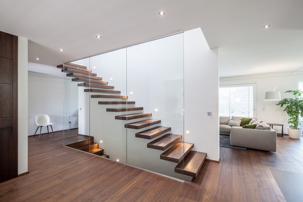 Imagen de escalera recta moderna grande con escalones de madera pintada y barandilla de vidrio