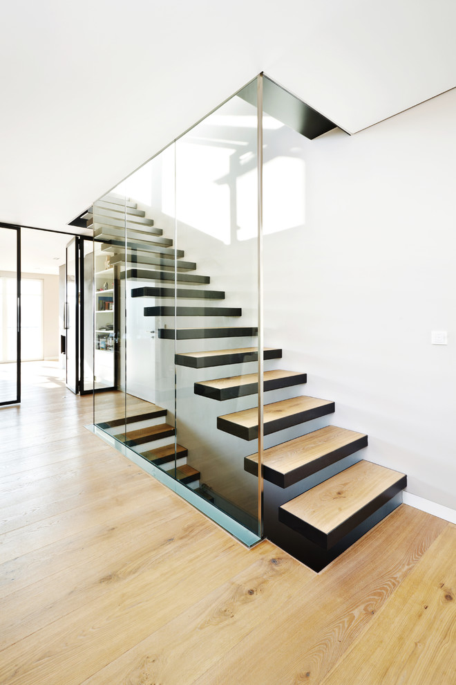 Photo of a medium sized contemporary wood floating staircase in Frankfurt with open risers and feature lighting.