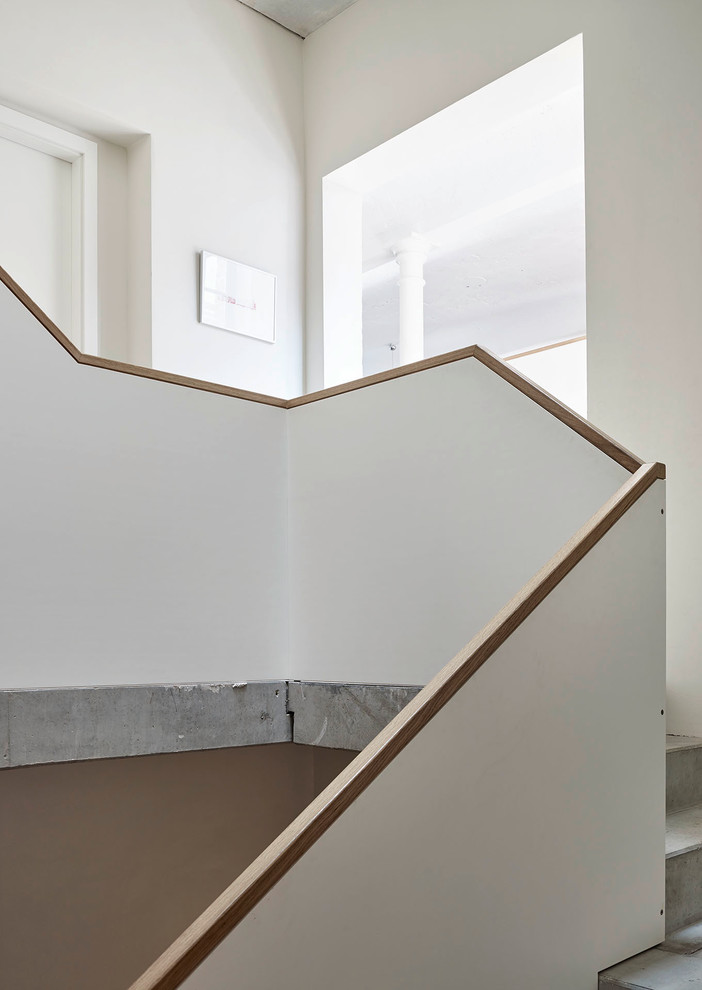 Стильный дизайн: огромная изогнутая бетонная лестница в стиле лофт с бетонными ступенями - последний тренд