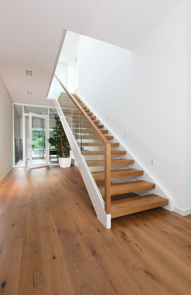 Large contemporary wood straight staircase in Bremen with open risers.