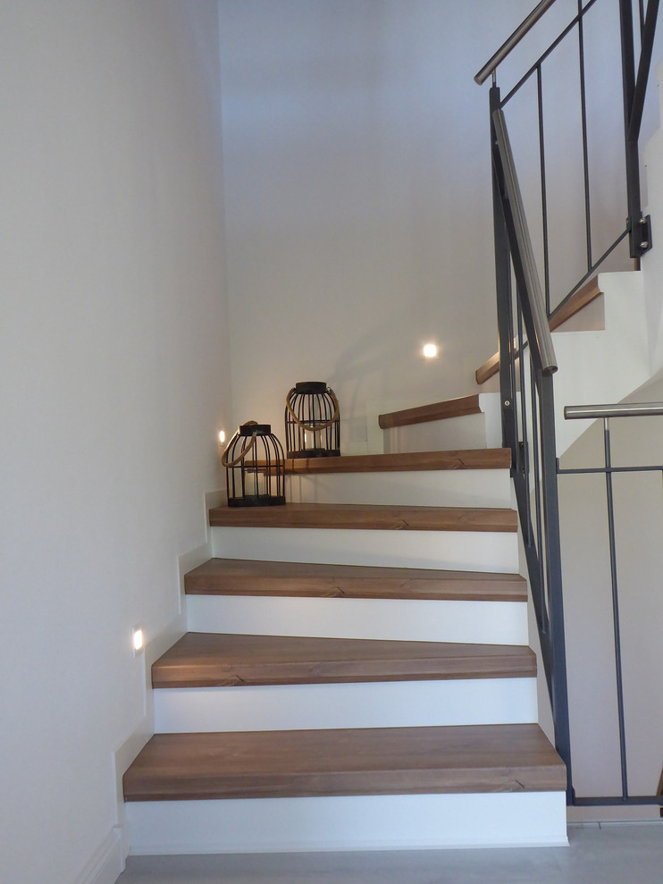 Ejemplo de escalera en U clásica de tamaño medio con escalones de madera, contrahuellas con baldosas y/o azulejos y barandilla de varios materiales
