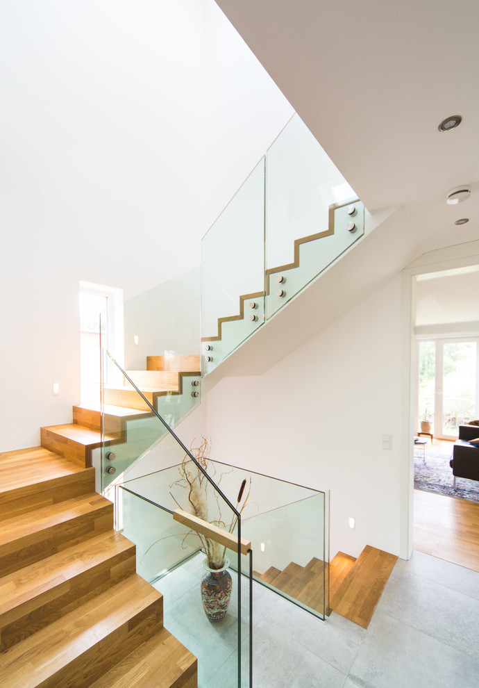 Foto de escalera en L contemporánea de tamaño medio con escalones de madera, contrahuellas de madera y barandilla de vidrio