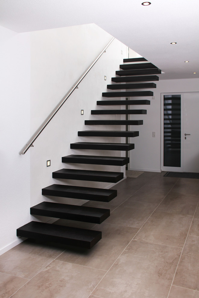 Foto de escalera recta actual con escalones de madera y barandilla de metal