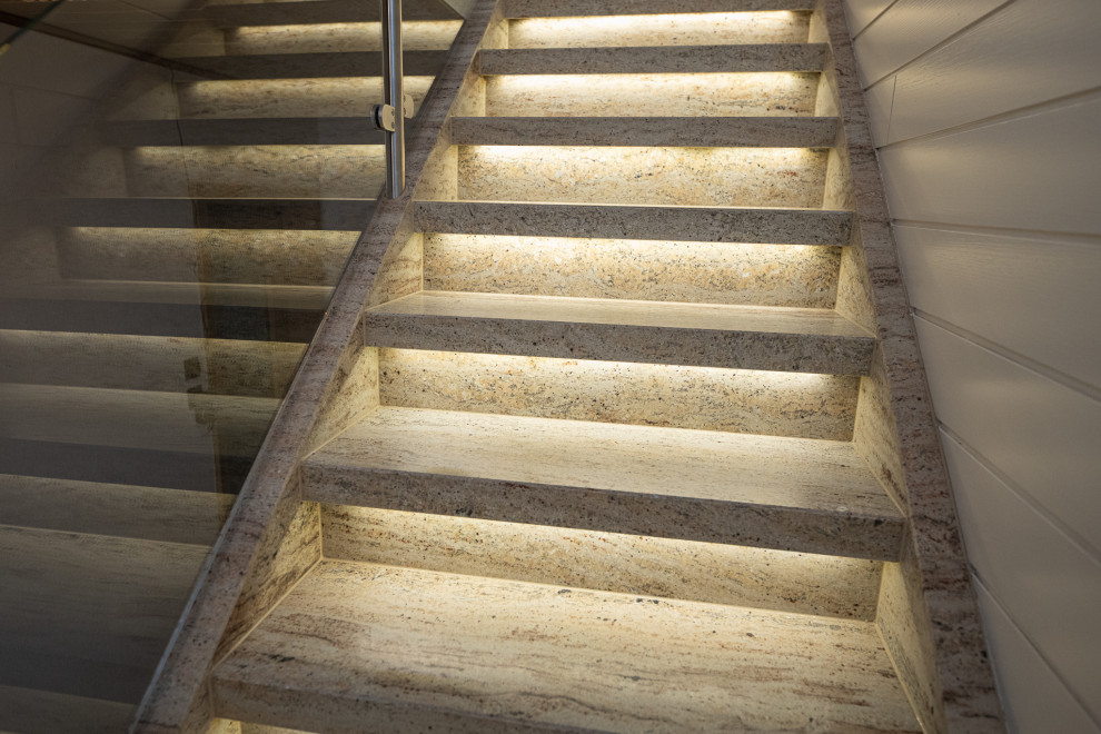 Exemple d'un escalier chic en L avec un garde-corps en verre et du lambris.