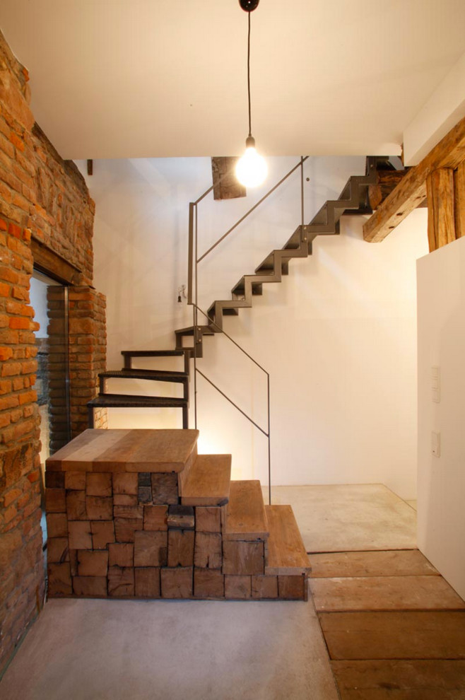 Bild på en liten rustik svängd trappa i metall, med öppna sättsteg