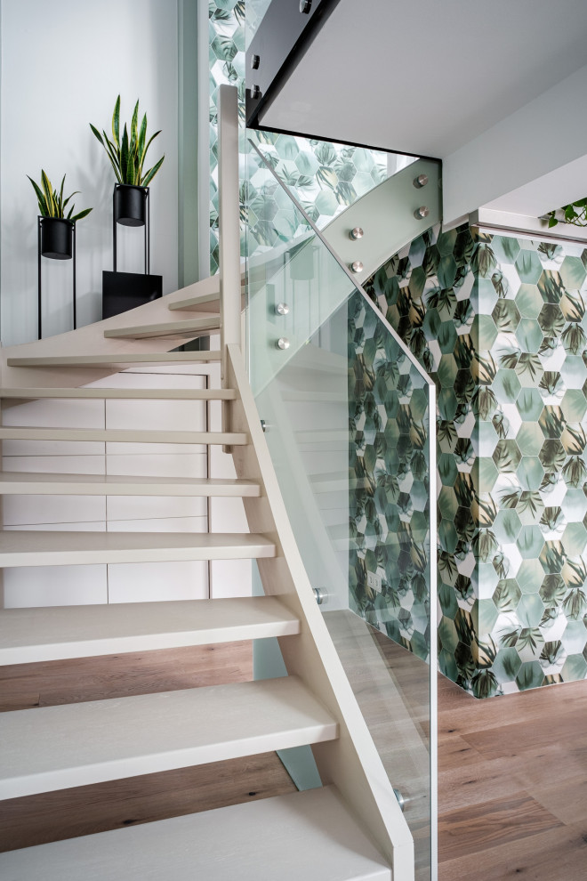 Medium sized contemporary wood curved glass railing staircase in Other with wallpapered walls.