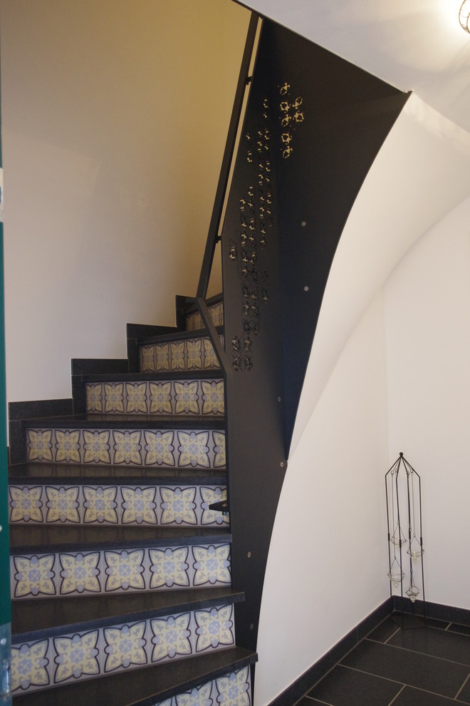 Gewendelte, Kleine Moderne Treppe mit gefliesten Treppenstufen, gefliesten Setzstufen und Stahlgeländer in Sonstige