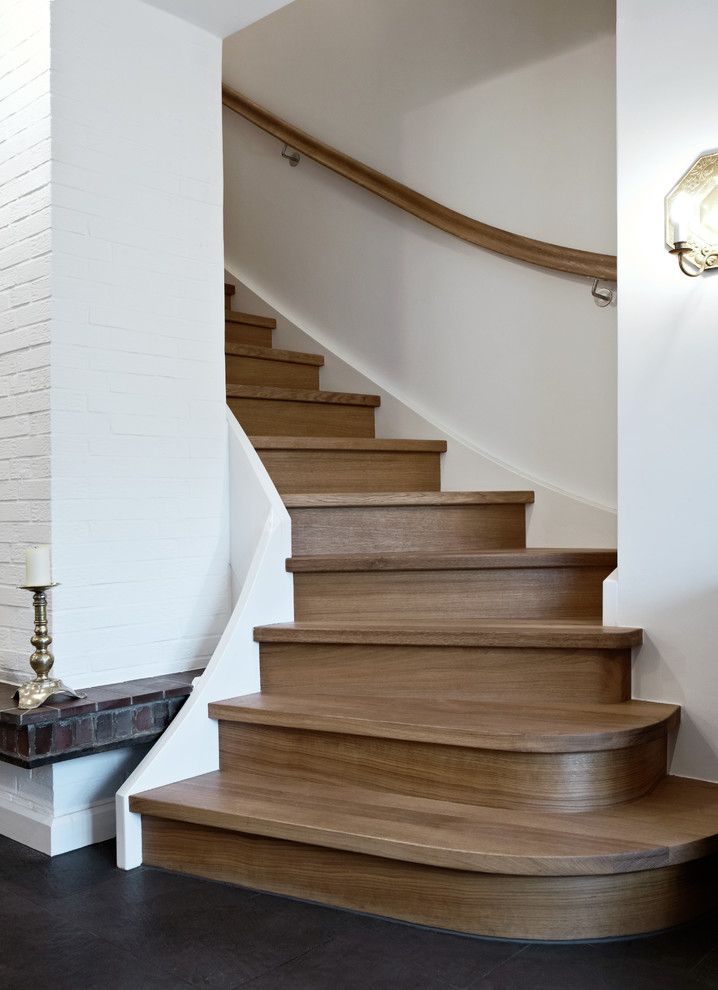 Идея дизайна: большая изогнутая деревянная лестница в классическом стиле с деревянными ступенями