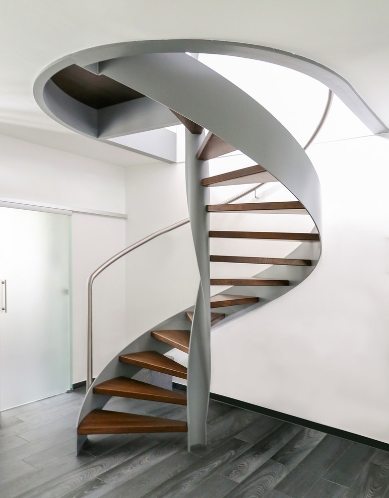 Imagen de escalera de caracol actual sin contrahuella con escalones de madera y barandilla de metal